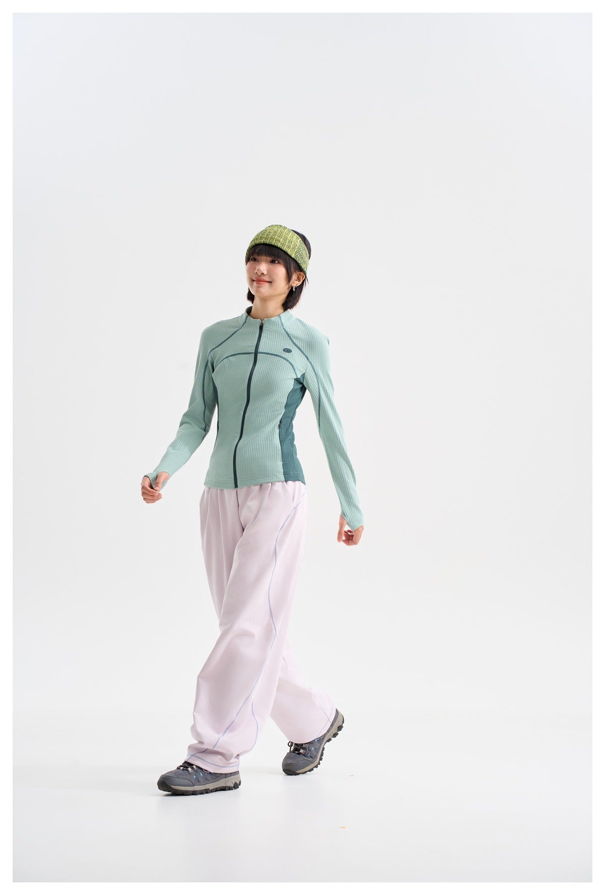Full-length model wearing a pale aqua zip-front jacket and loose pale lavender pants.