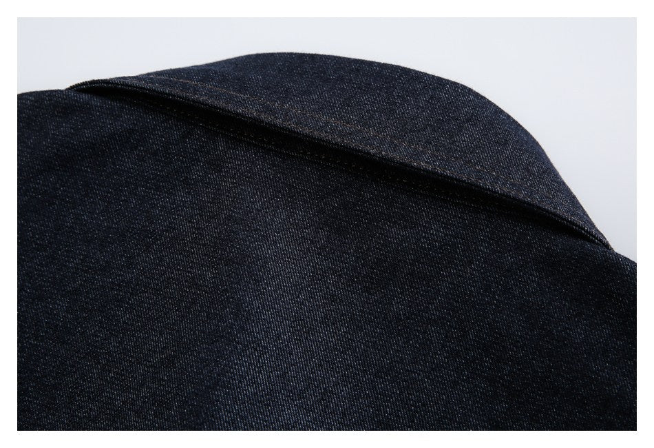 Close-up of a folded edge in dark indigo denim with brown topstitching.