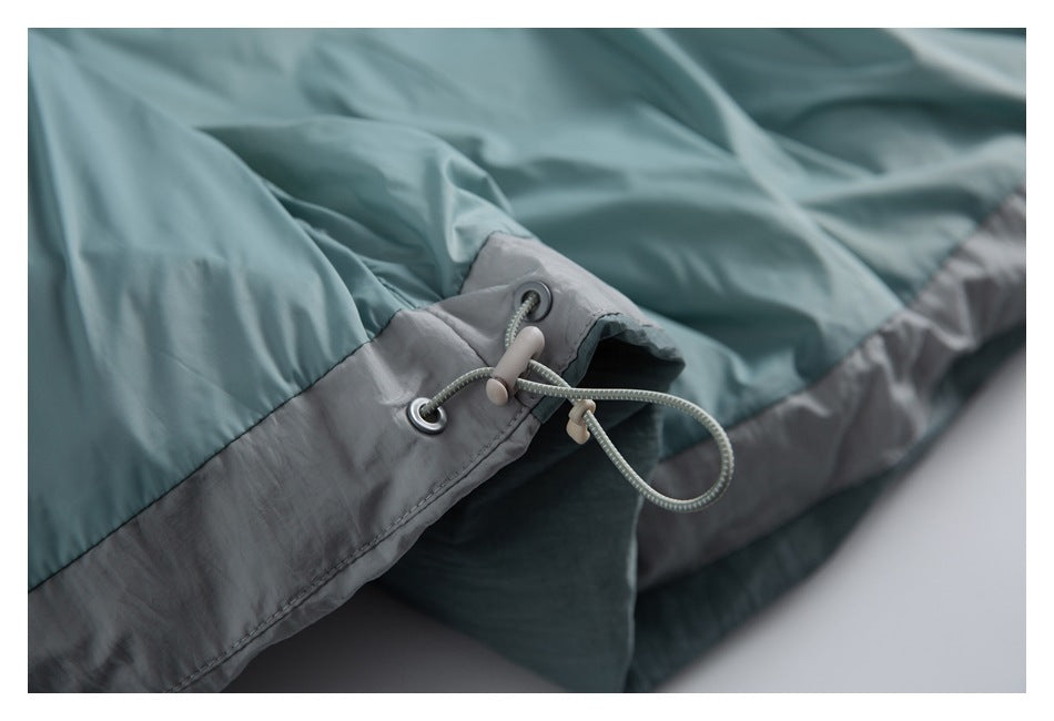 Close-up of the jacket hem's adjustable drawcord, eyelets, and toggles on teal and gray panels.