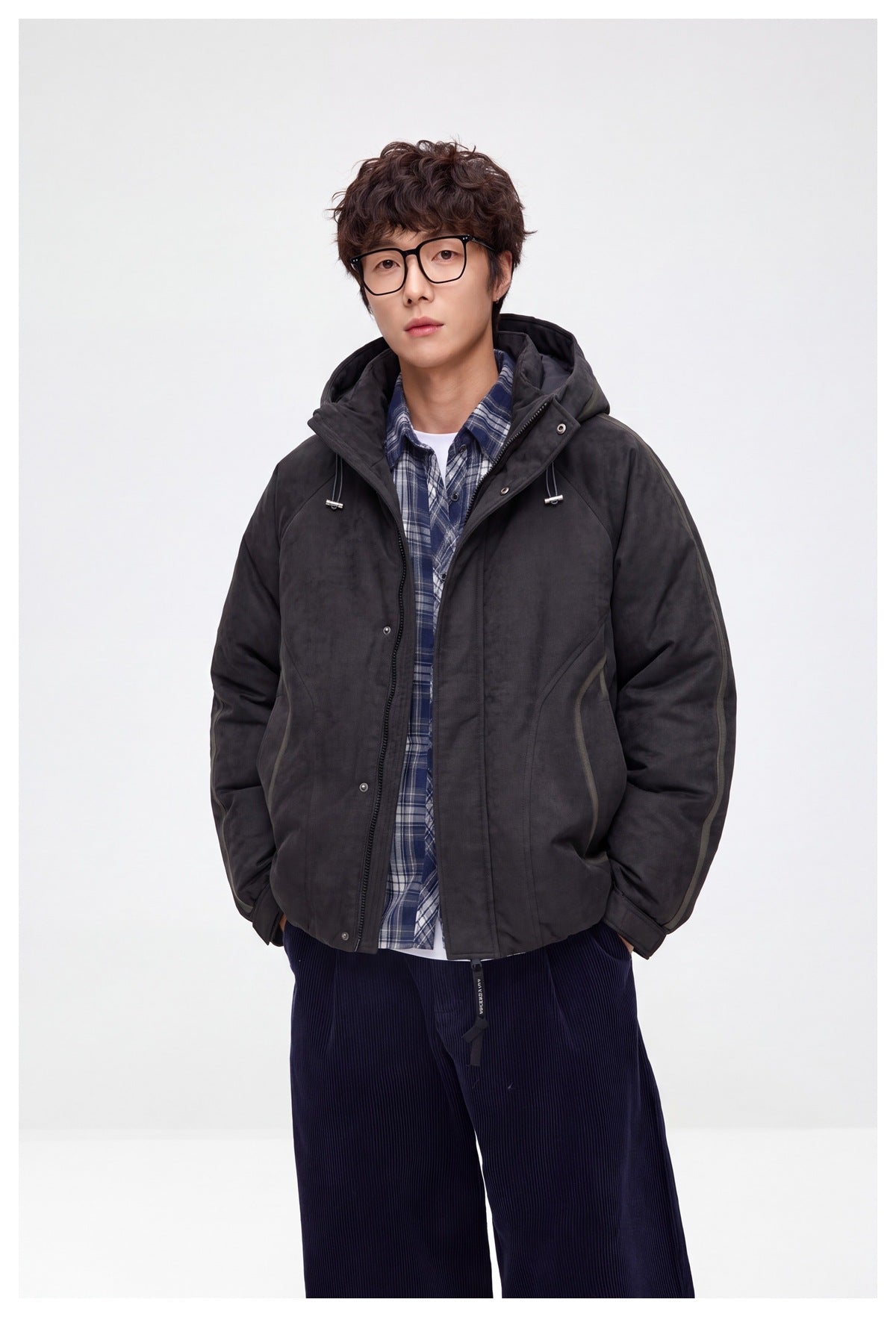 Model wearing an open charcoal hooded jacket over a blue plaid shirt, shown from the waist up.