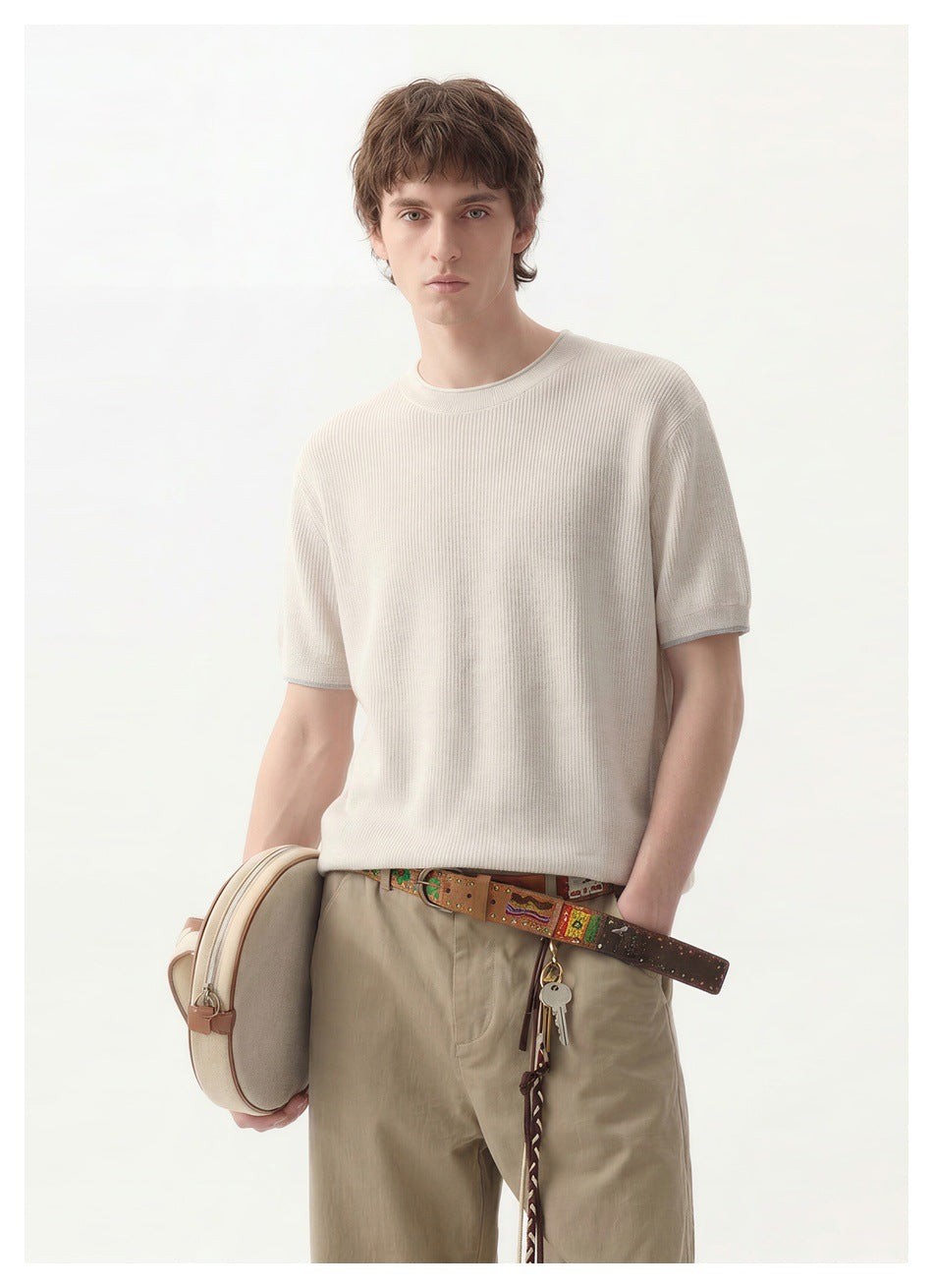 Model wearing an ivory short-sleeve knit crewneck with taupe trousers, shown from the front.