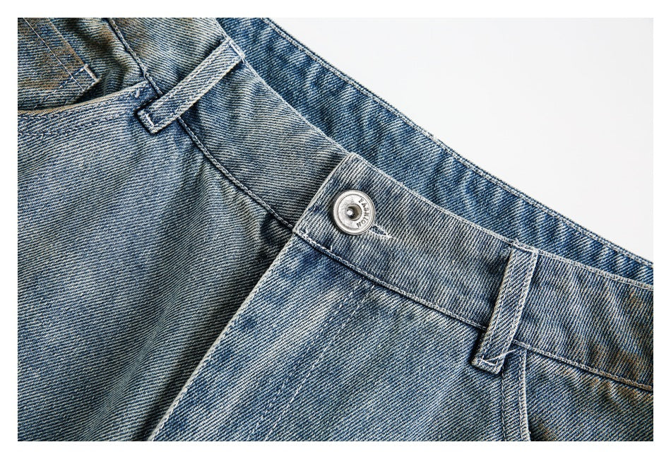 Close-up of light blue faded jeans showing the waistband, belt loop, and metal button.
