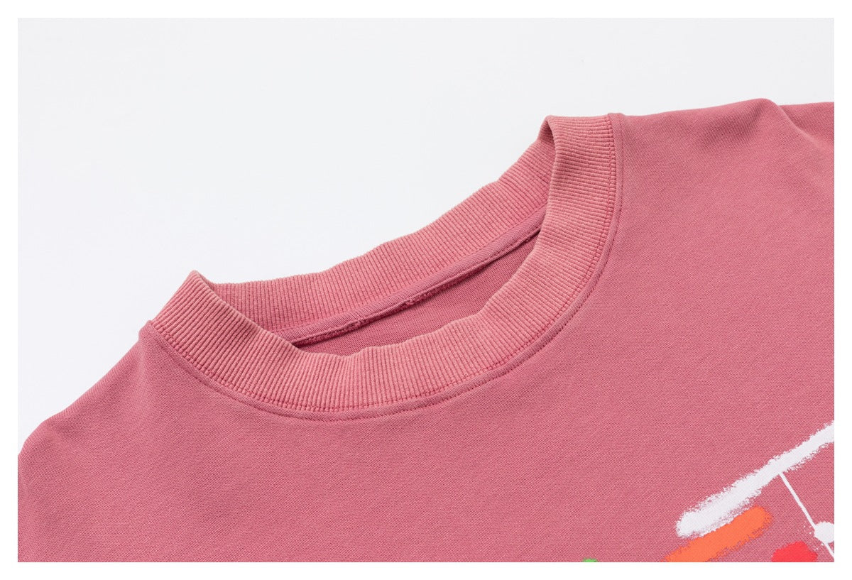 Close-up of a dusty rose sweatshirt's ribbed crew neckline and partial multicolored abstract print.