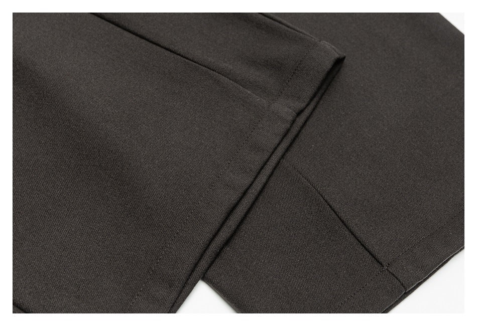 Close-up of dark charcoal trousers showing stitched hems and overlapping fabric panels.