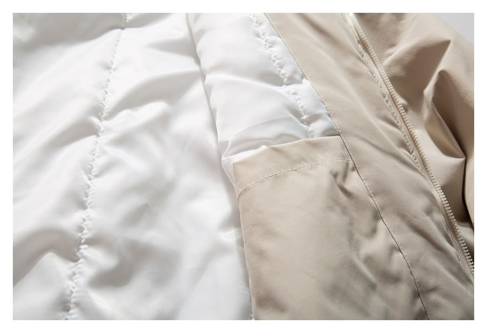 Close-up of white quilted jacket lining beside a tan panel, pocket seam and zipper.