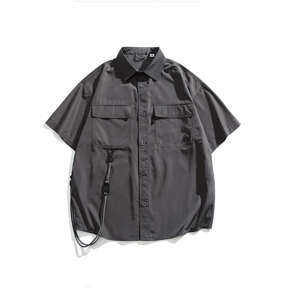 Gray short-sleeve button-up shirt with two flap chest pockets, embroidered logo and a hanging cord, flat lay front view