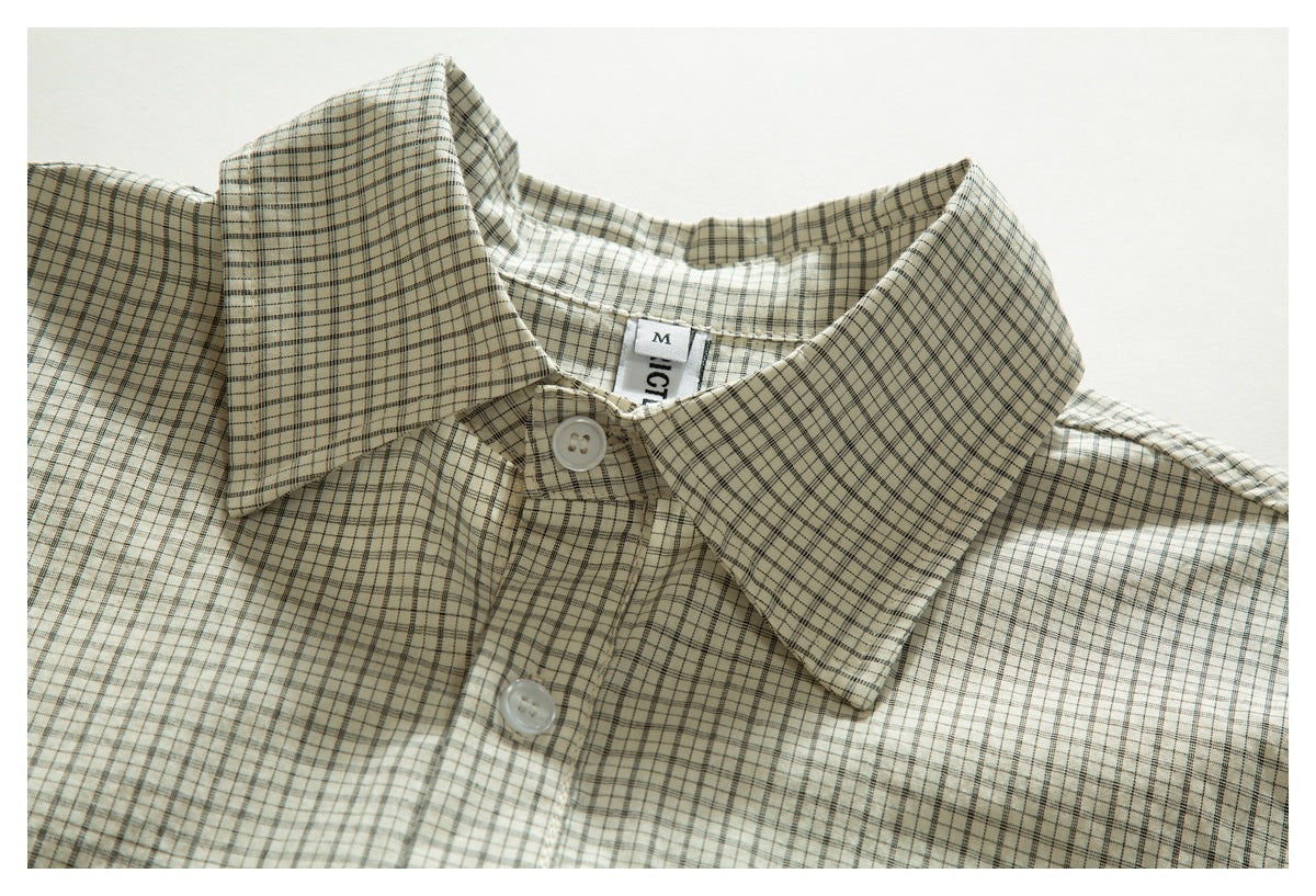 Close-up of a cream plaid shirt collar and white buttons, with a partially visible neck label.