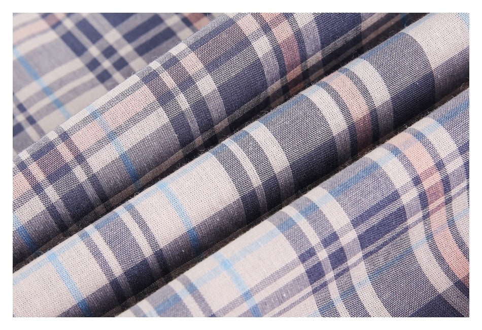 Close-up of folded plaid fabric in beige, navy, gray, and pale blue, showing its woven texture.