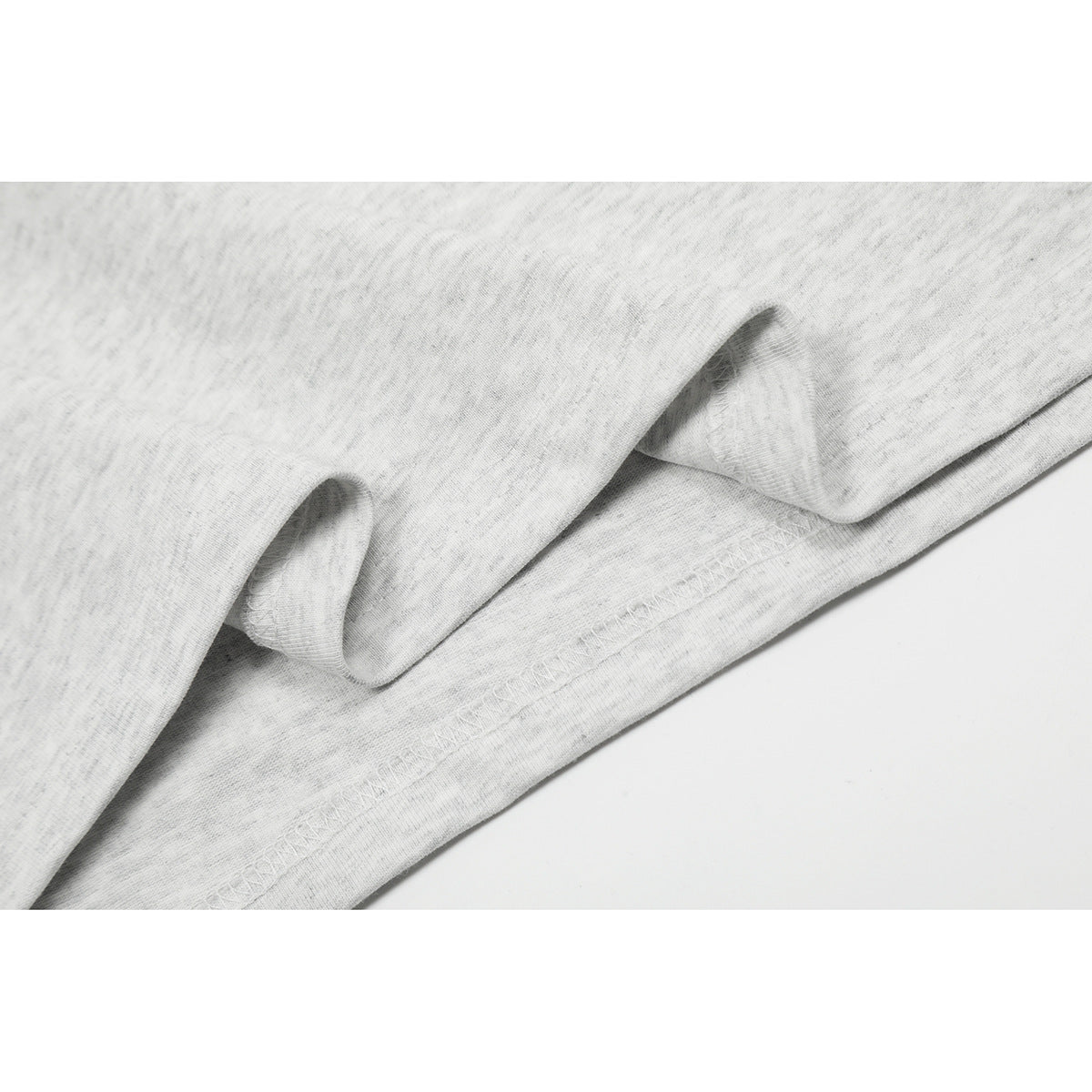 Close-up of the light heather-gray T-shirt fabric folded to show its stitched lower hem.