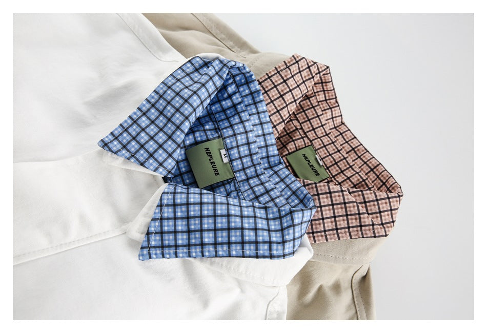 Close-up of white and beige jacket collars with blue and pink checked lining and sewn-in labels.