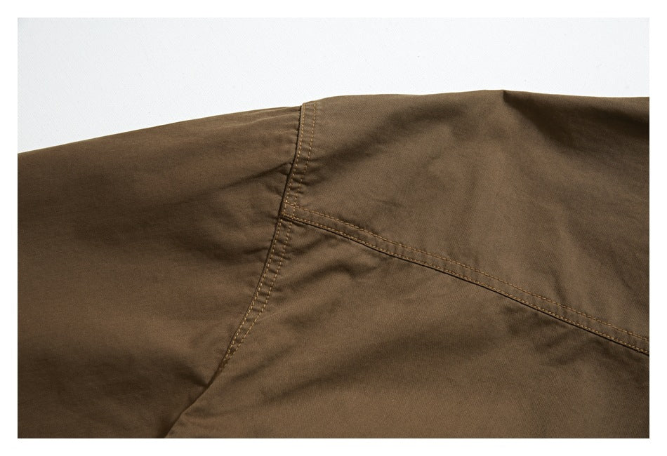 Close-up of a brown garment showing a curved panel seam with double stitching.