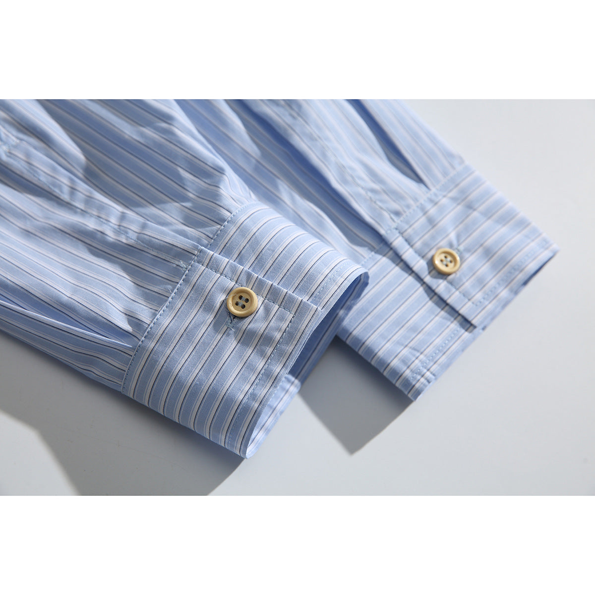 Close-up of the light blue striped shirt's long sleeves and buttoned cuffs.