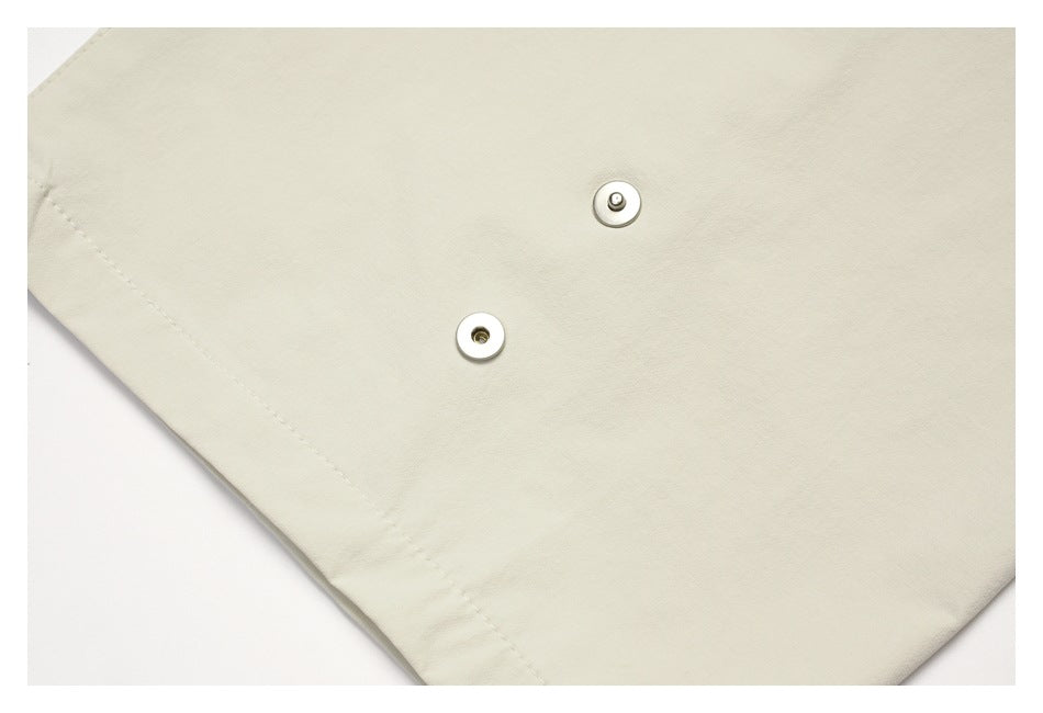 Close-up of two metal snap fastener halves on cream fabric.