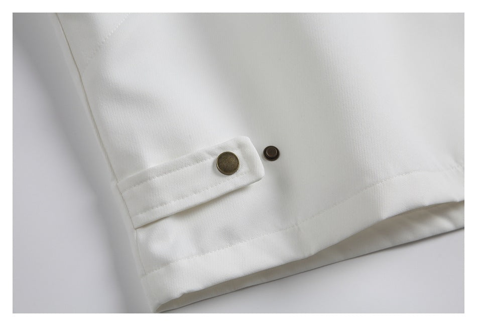 Close-up of a white garment hem with a snap-fastened tab and bronze-tone hardware.