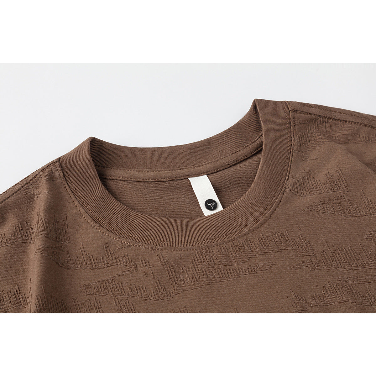 Close-up of a brown crew-neck T-shirt showing its ribbed collar and subtle textured pattern.