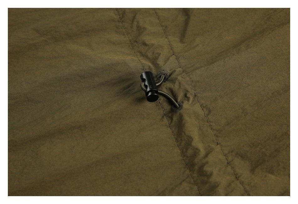 Close-up of an olive garment's stitched seam and black cord-lock toggle.