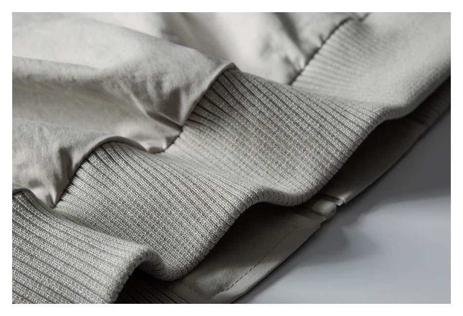 Close-up of a wide ribbed knit cuff attached to light gray jacket fabric.