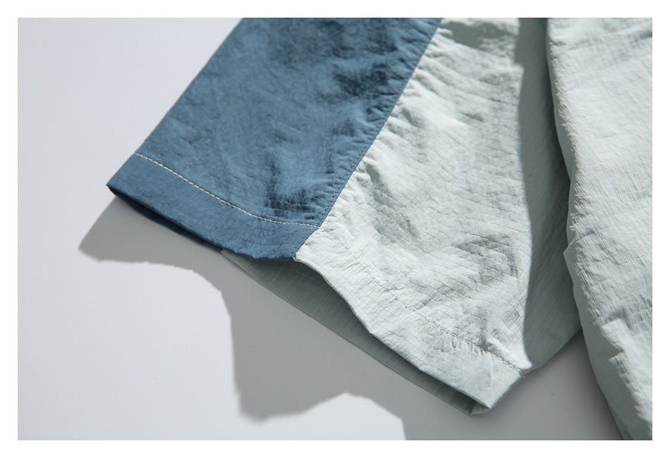 Close-up of the shirt's short sleeve, showing dark blue and pale sage color-block panels and stitching.