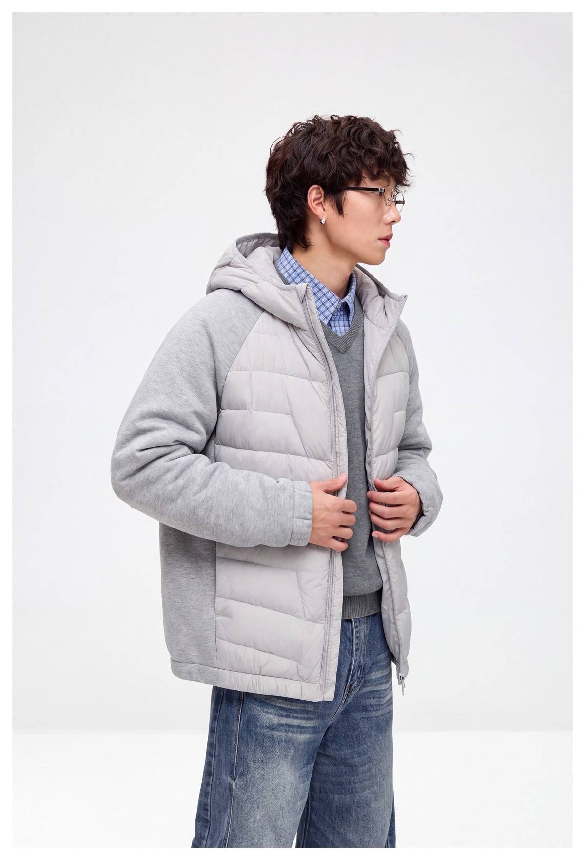 Model wearing the light gray hooded jacket partly unzipped, showing its quilted front and heather gray sleeves.