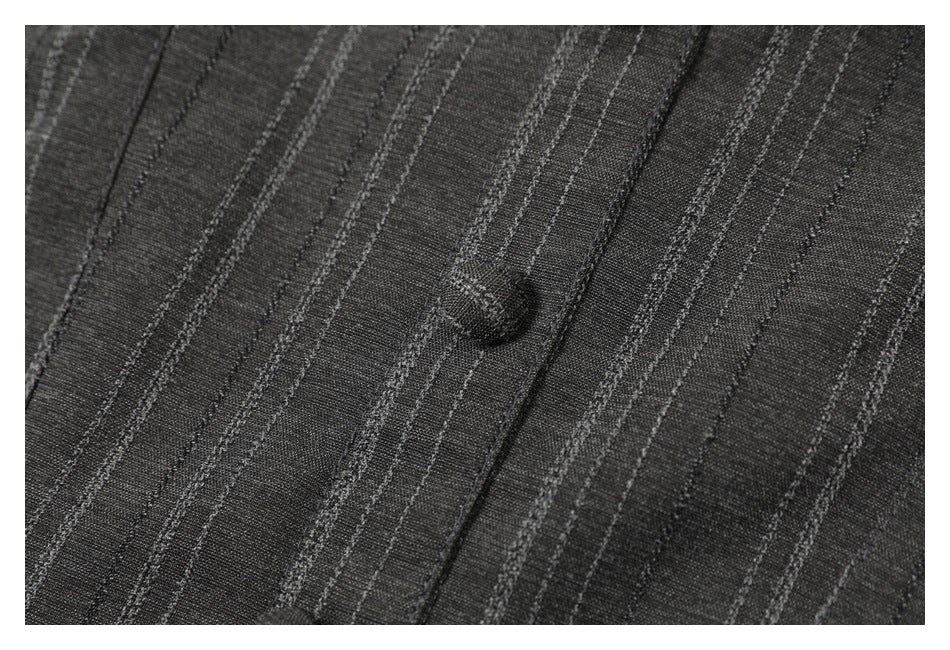 Close-up of a fabric-covered button on the charcoal garment's pinstriped front.