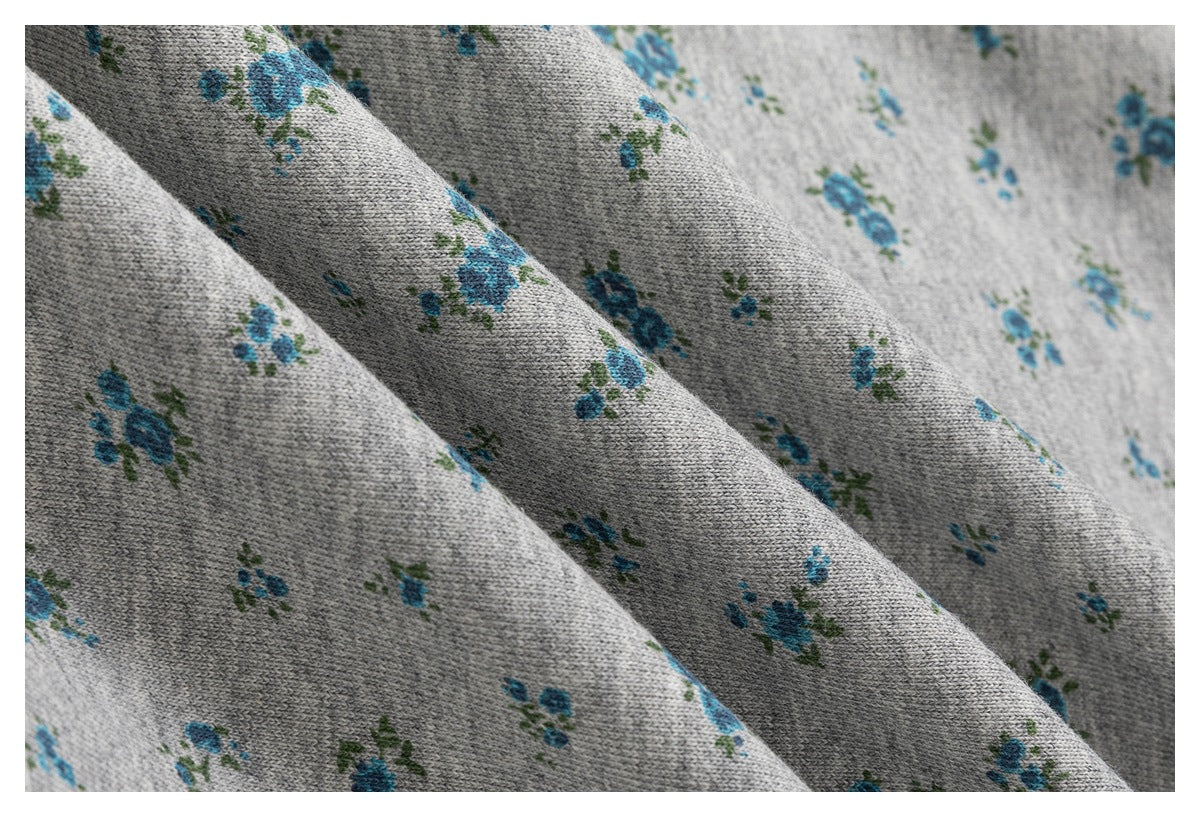 Macro view of the gray knit fabric with a small blue-and-green floral print.