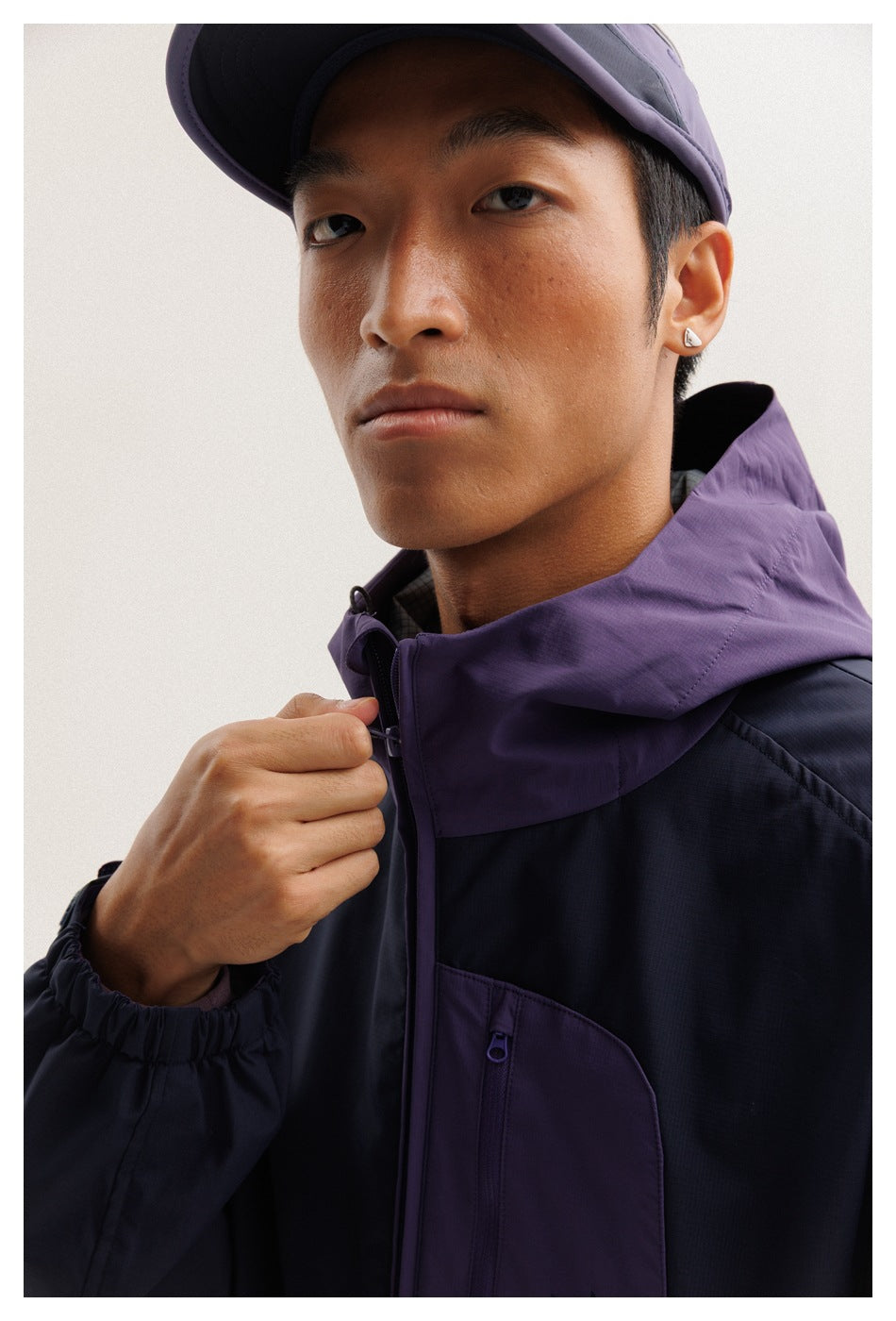 Close-up of the model wearing the jacket, showing its purple hood, front zipper, and chest pocket.