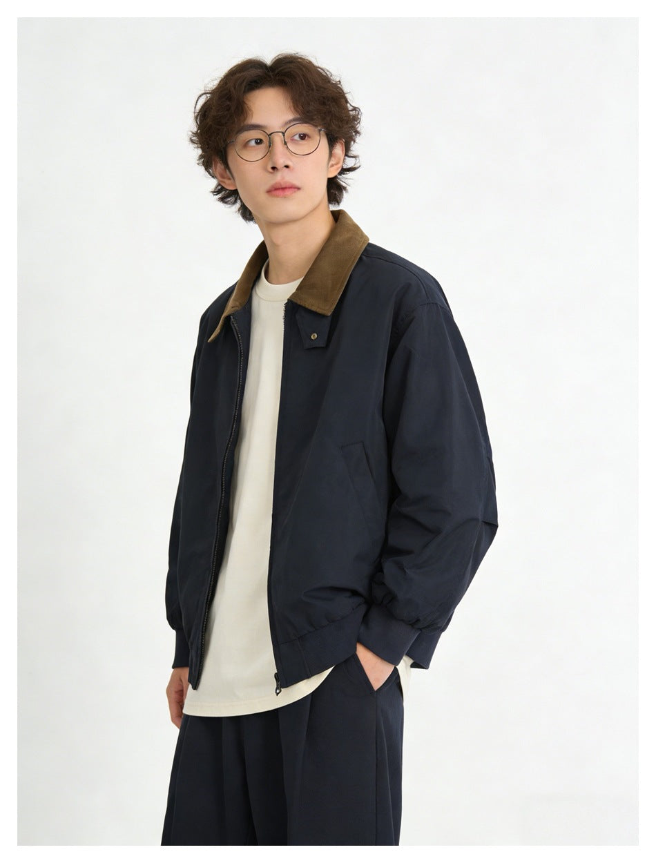 Model wearing a dark navy zip jacket with a brown collar over a white shirt, shown from the front at an angle.