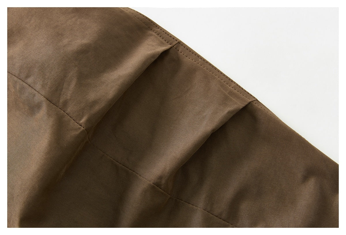 Close-up of brown garment fabric with a curved double-stitched edge and panel seam.