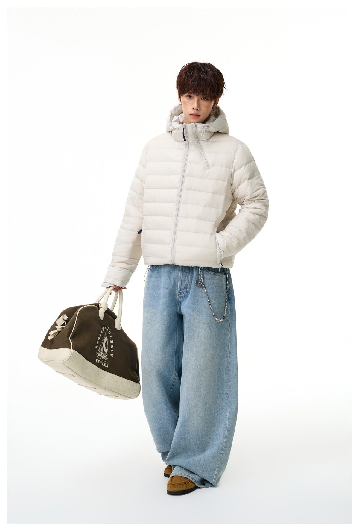 Full-length model wearing an ivory hooded puffer jacket and light blue wide-leg jeans, holding a two-tone bag.