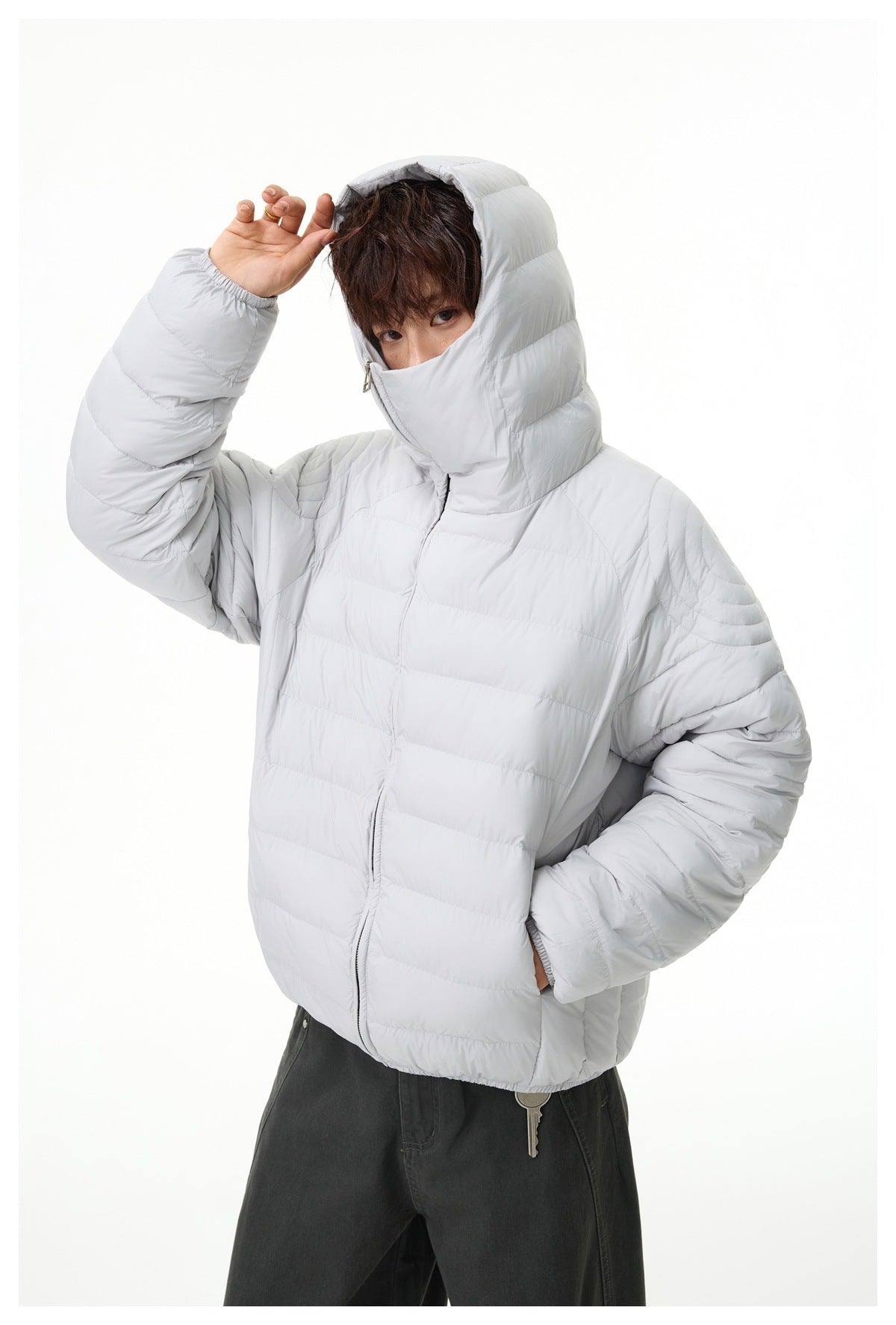 Close view of a model wearing a light gray quilted jacket with an oversized hood and high collar.