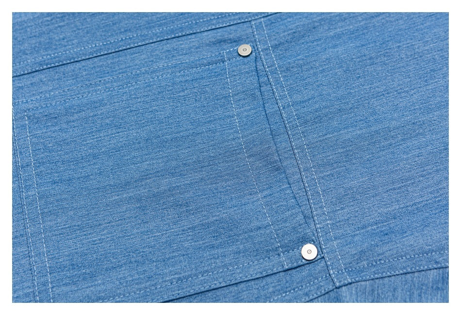 Close-up of the blue shirt’s rectangular patch pocket, stitching, and two metal rivets.