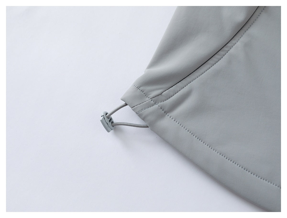 Close-up of a light gray garment hem with an elastic drawcord and toggle.