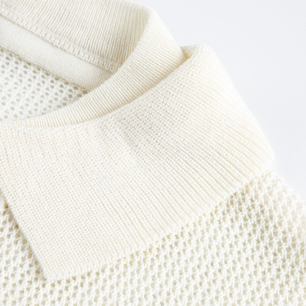 Close-up of an ivory knit polo shirt's ribbed collar and open-knit body.