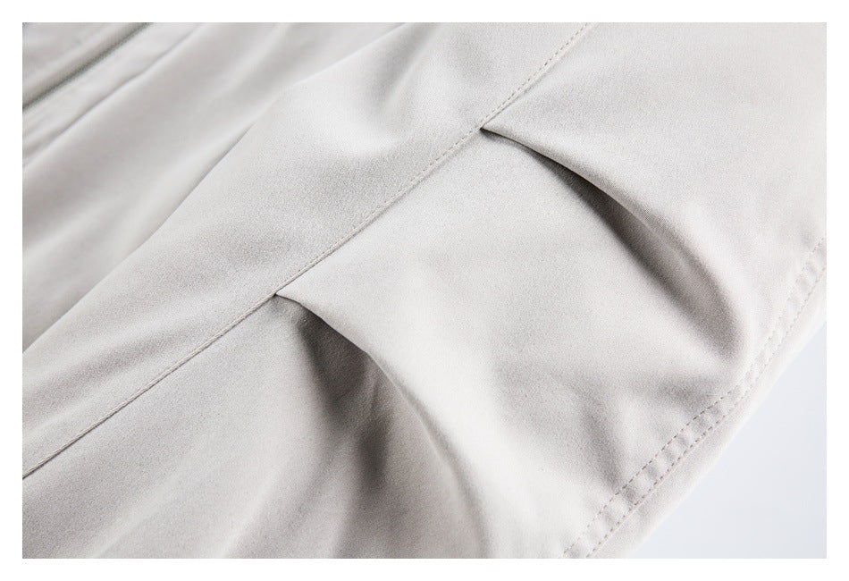 Close-up of a light gray jacket panel with a folded seam and stitching.