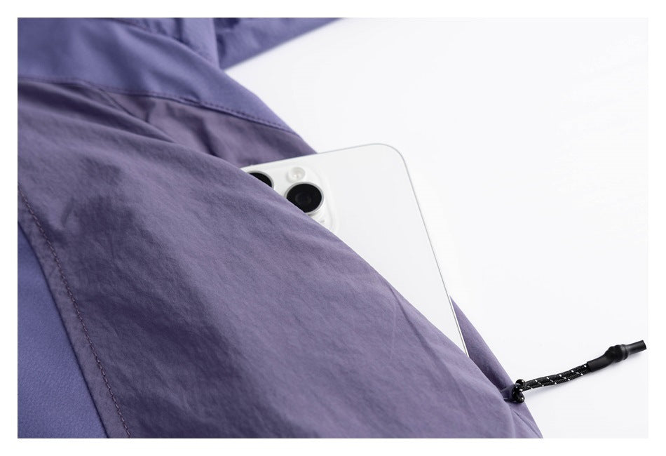 Close-up of a lavender garment with a pocket holding a white phone and a black drawcord.