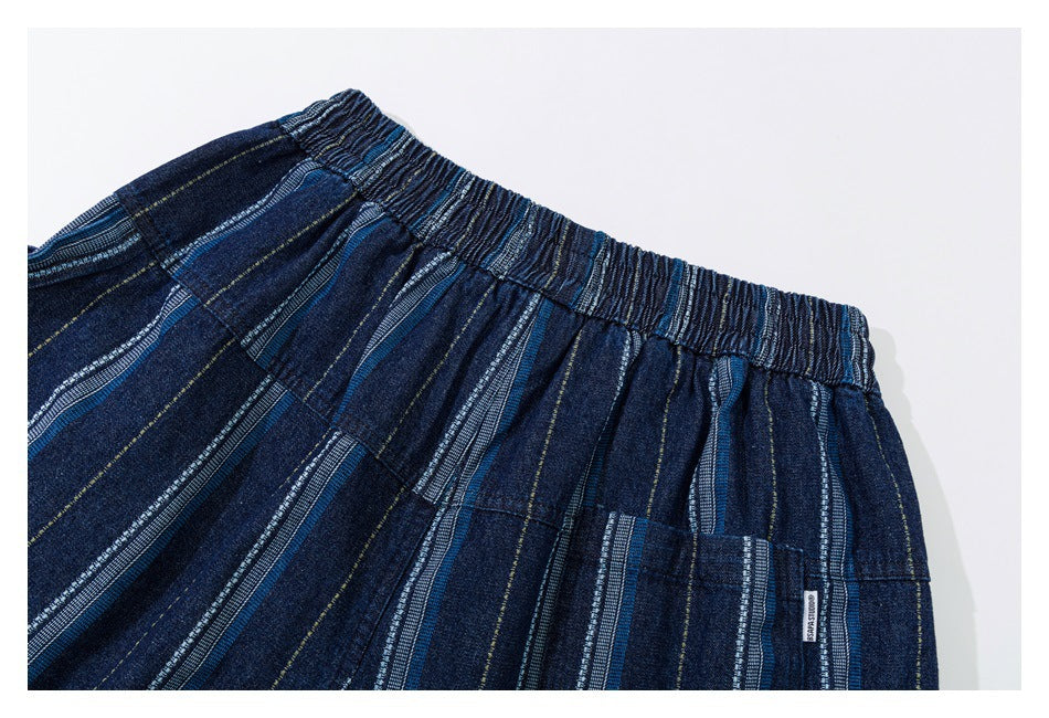Close-up of the gathered elastic waistband and pocket on dark blue shorts with multicolored vertical stripes.