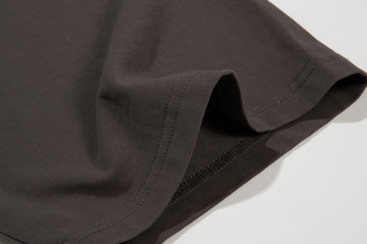 Close-up of a dark brown garment hem with double stitching and overlocked seam.