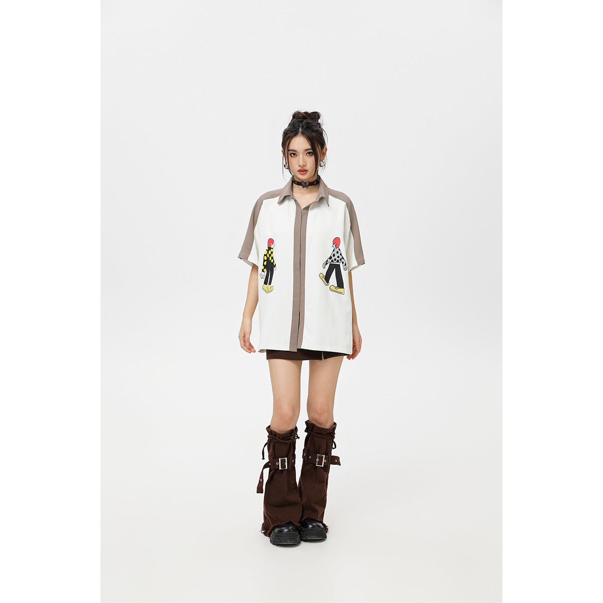Full-length front view of a model wearing an oversized white shirt with taupe trim and two cartoon prints.