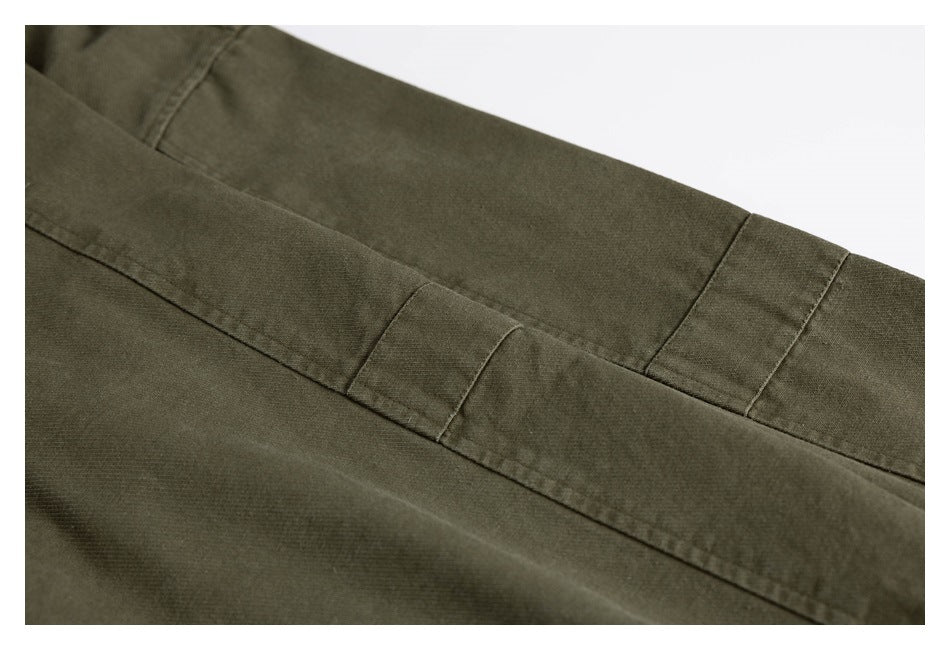Close-up of olive-green garment fabric with stitched panels and a narrow overlapping seam.