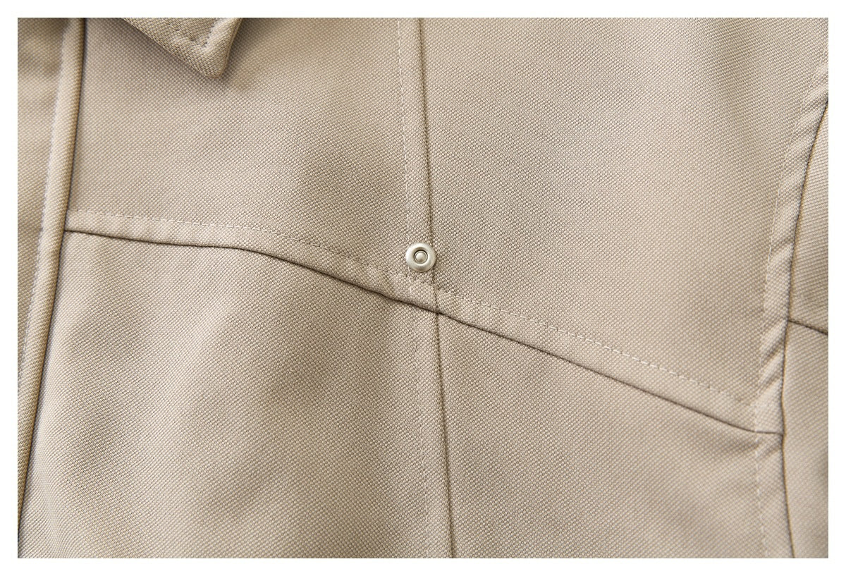 Close-up of beige jacket fabric with a curved stitched seam and metal snap.