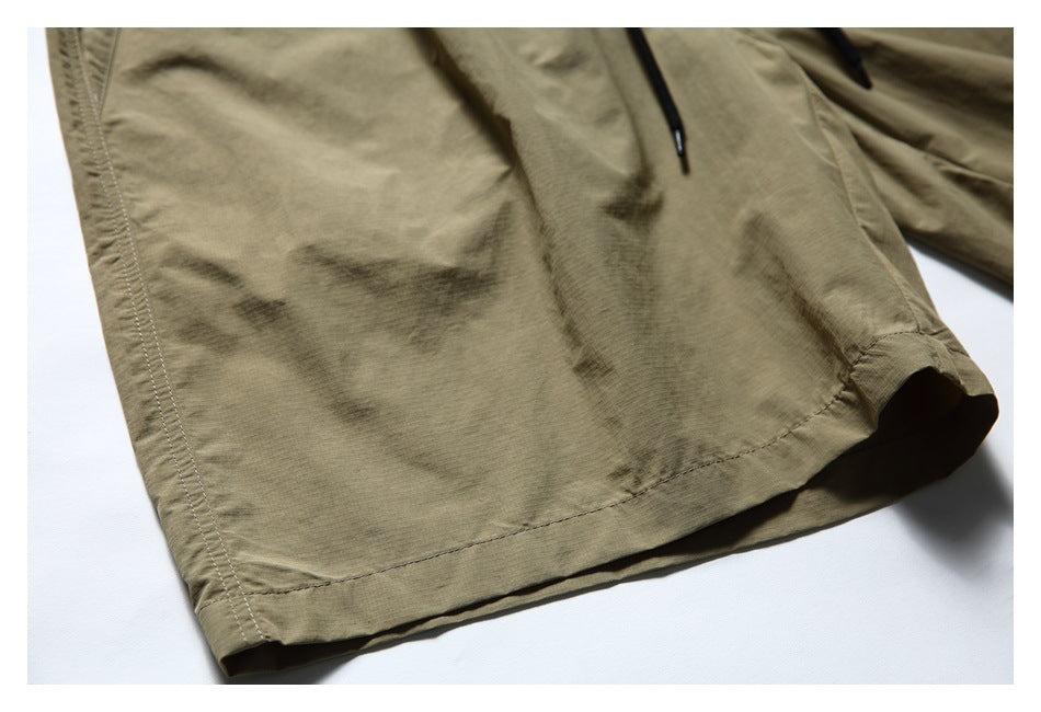 Close-up of the olive-khaki shorts leg, showing the hem stitching and part of a black drawstring.