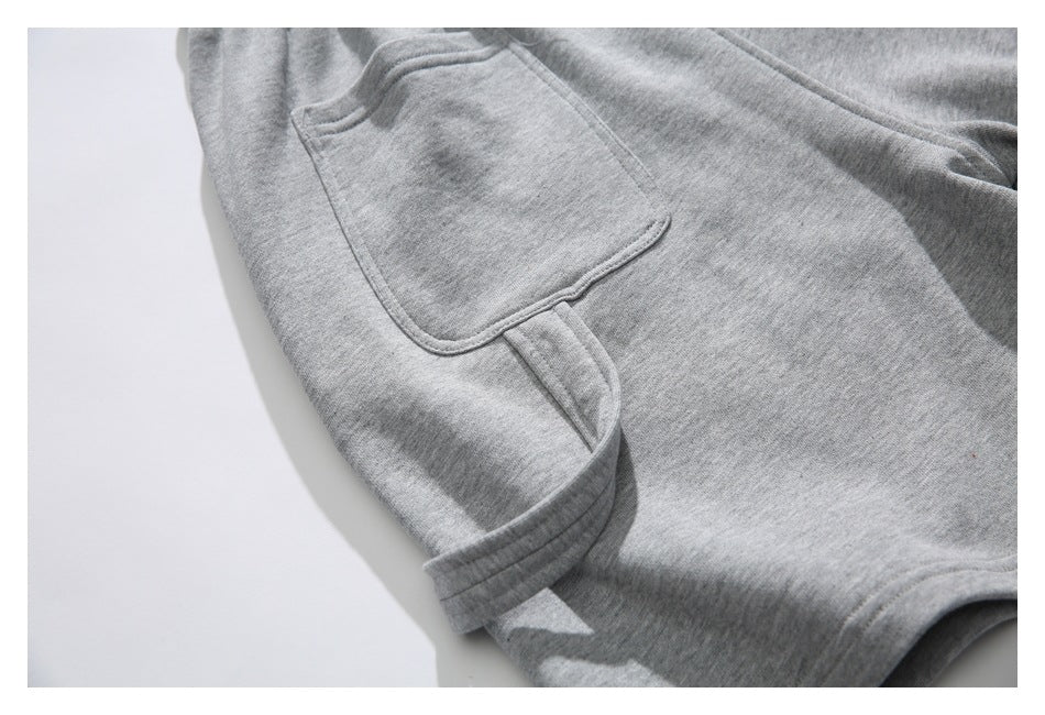 Close-up of gray shorts showing a large patch pocket and stitched hem.