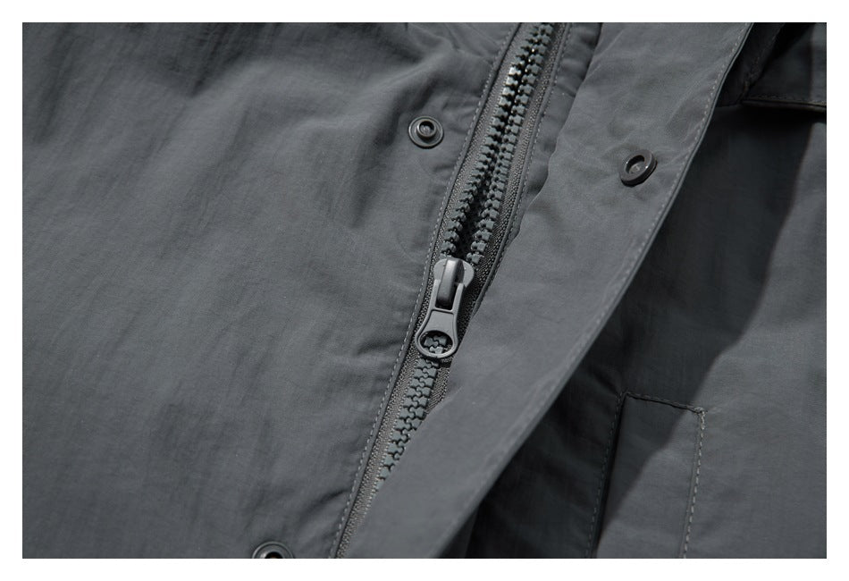Close-up of a dark gray jacket's front zipper, snap buttons, and storm flap.
