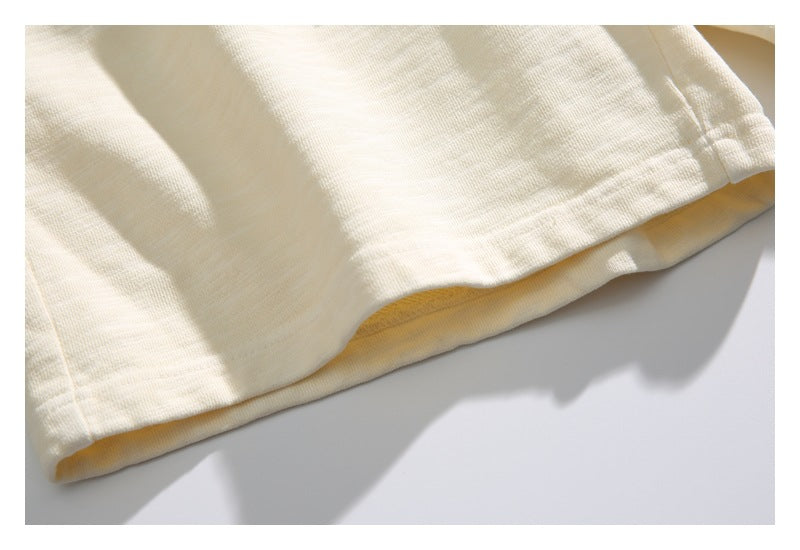 Close-up of the stitched hem on the cream shorts.