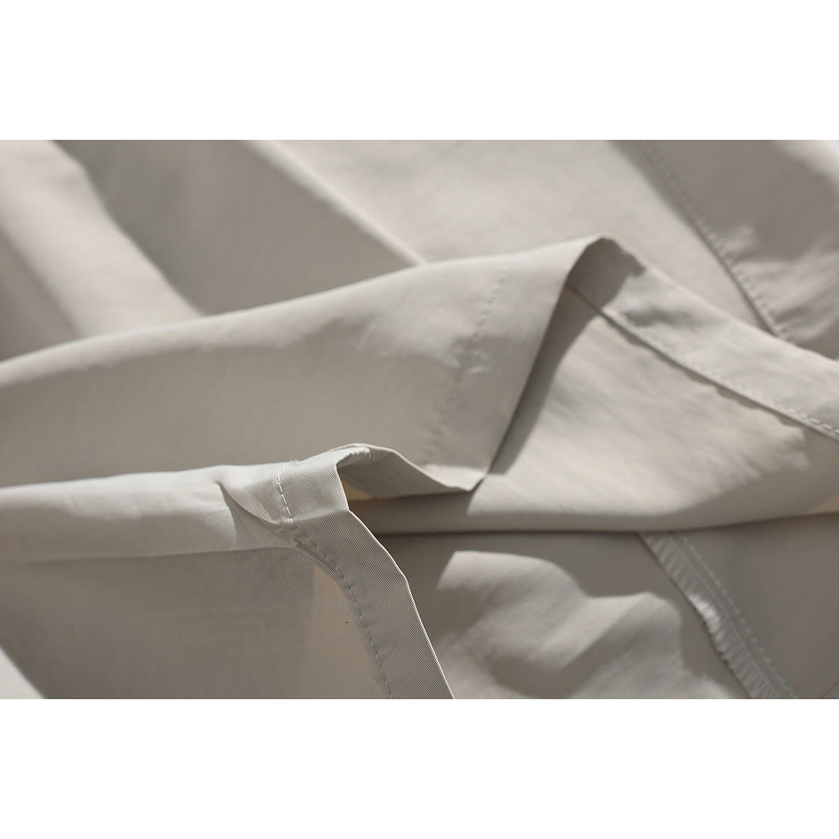 Close-up of light beige shorts showing a pocket edge, fabric folds, and stitching.