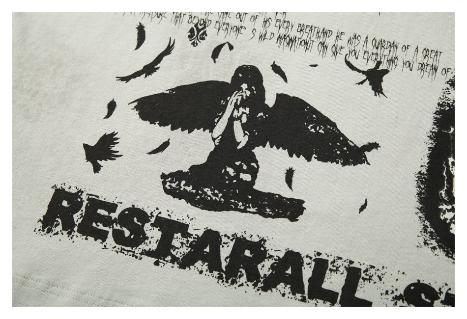 Close-up of a distressed black bird illustration and bold lettering printed on off-white T-shirt fabric.