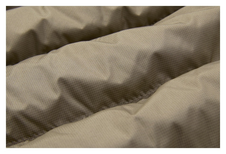 Extreme close-up of the tan jacket's fine grid-textured fabric and stitched seam.