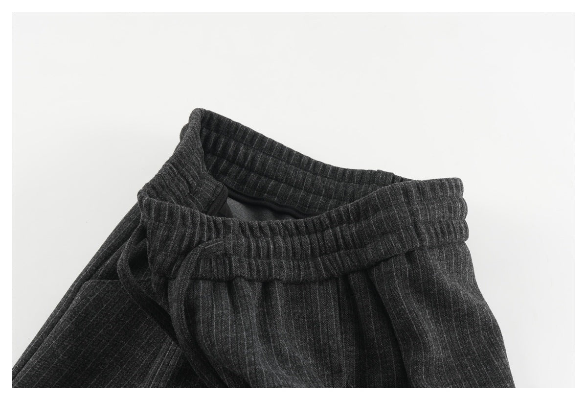 Close-up of the charcoal pinstripe trousers’ elastic waistband and drawstring, turned to reveal the inside.