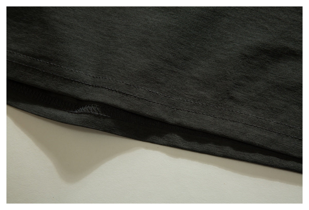 Close-up of the dark charcoal garment's stitched hem and overlocked seam.