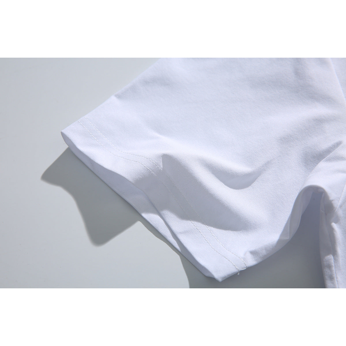 Close-up of the white T-shirt's sleeve hem and double stitching.